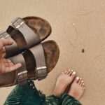 person holding pair of brown-and-black open toe sandals